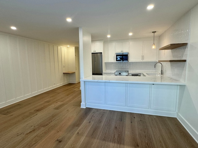 kitchen featuring sink, stainless steel appliances, dark hardwood / wood-style floors, kitchen peninsula, and decorative light fixtures