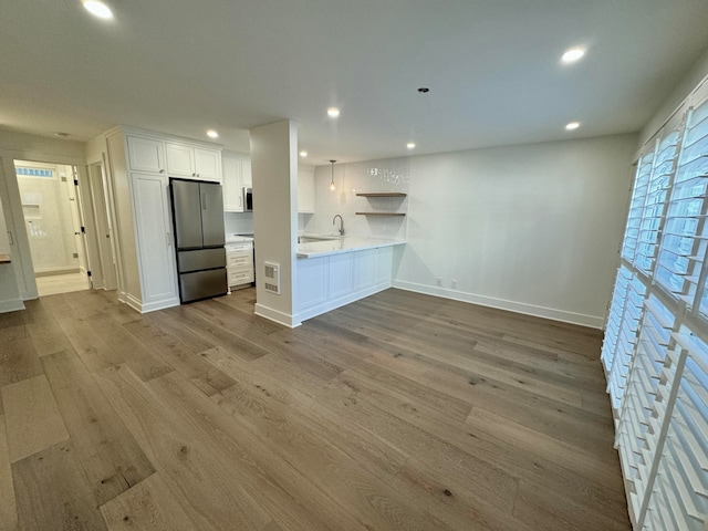 kitchen featuring white cabinetry, light wood-type flooring, kitchen peninsula, and stainless steel appliances