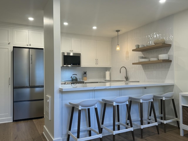 kitchen featuring appliances with stainless steel finishes, a kitchen breakfast bar, dark hardwood / wood-style flooring, and white cabinets