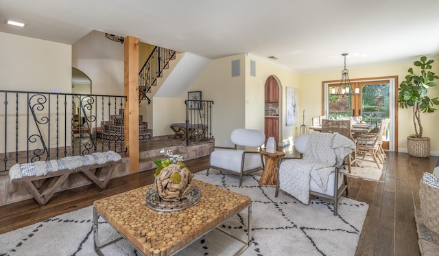 living room featuring hardwood / wood-style floors, crown molding, and an inviting chandelier