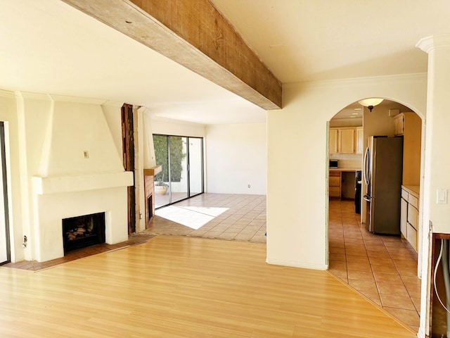 unfurnished living room featuring beamed ceiling, a large fireplace, and light hardwood / wood-style floors