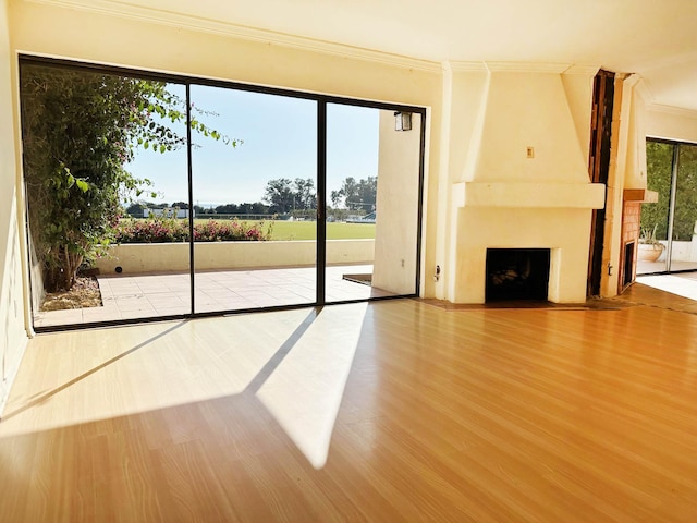 unfurnished living room featuring a fireplace, hardwood / wood-style floors, and crown molding