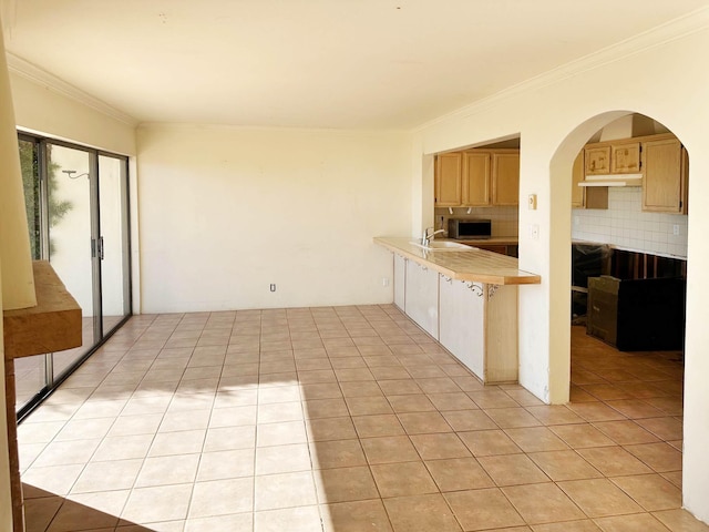 kitchen with sink, backsplash, kitchen peninsula, crown molding, and light tile patterned flooring