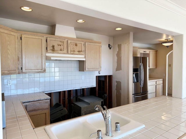 kitchen with decorative backsplash, sink, light brown cabinets, tile countertops, and stainless steel fridge with ice dispenser