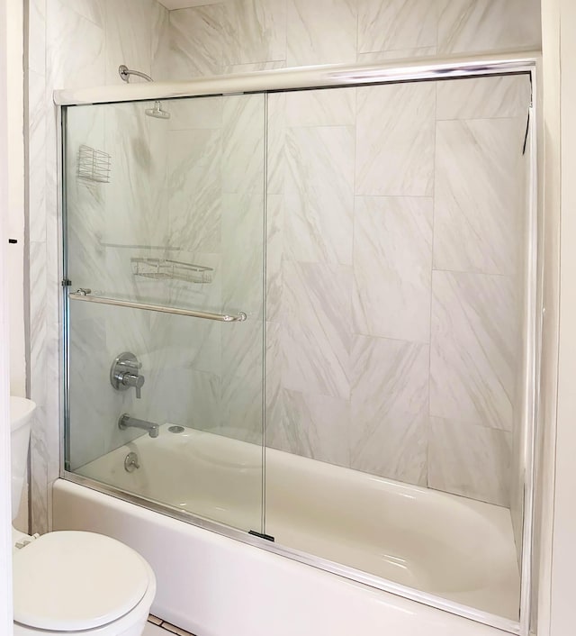 bathroom with toilet and combined bath / shower with glass door