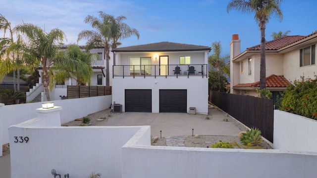 view of front of property featuring a balcony, a garage, and central air condition unit