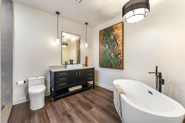 bathroom with a tub, hardwood / wood-style floors, vanity, and toilet