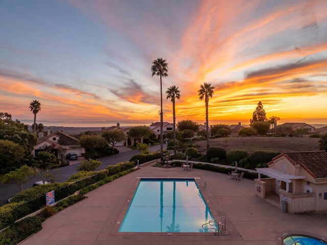 pool at dusk with a patio area