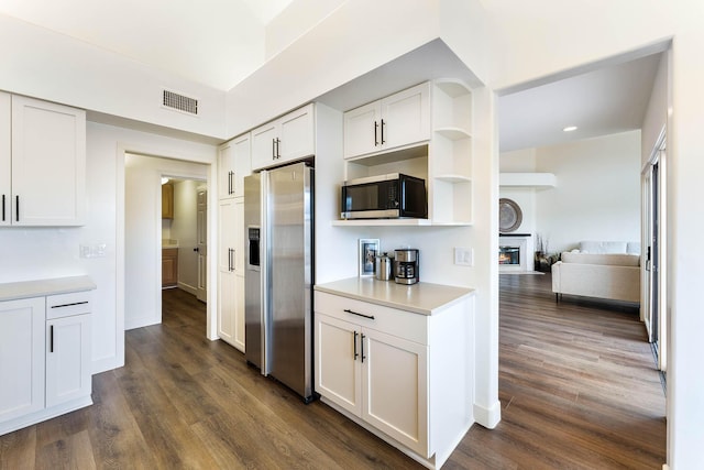 kitchen with stainless steel appliances, white cabinetry, and dark hardwood / wood-style floors