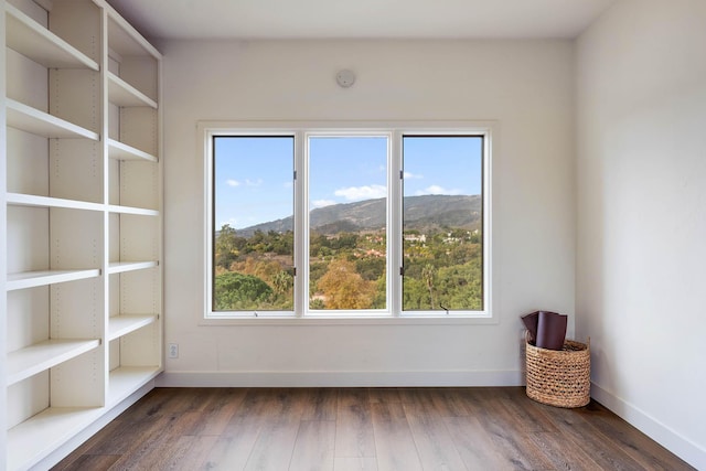 unfurnished room with a wealth of natural light, a mountain view, and dark hardwood / wood-style flooring