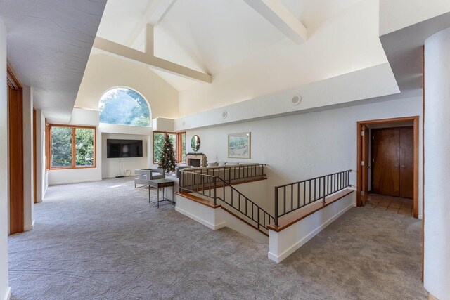 interior space featuring carpet flooring, beam ceiling, and high vaulted ceiling