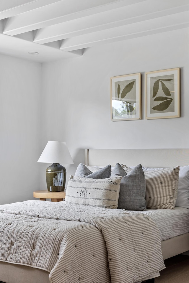 bedroom with beamed ceiling and hardwood / wood-style floors