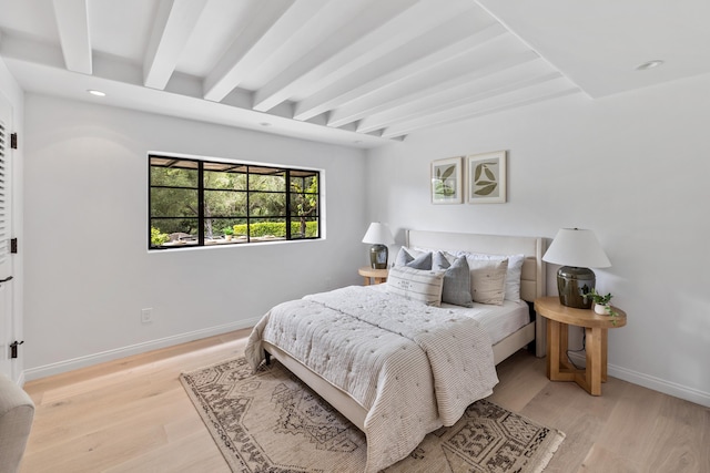 bedroom featuring beam ceiling and light hardwood / wood-style flooring