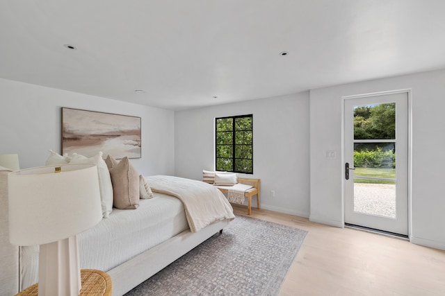 bedroom featuring access to outside, multiple windows, and light wood-type flooring