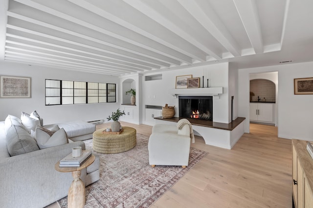 living room with light hardwood / wood-style flooring, beamed ceiling, and a baseboard heating unit