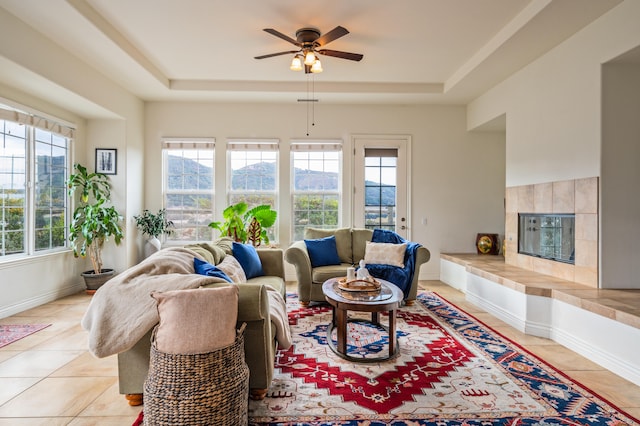 living room featuring a raised ceiling, a wealth of natural light, and ceiling fan