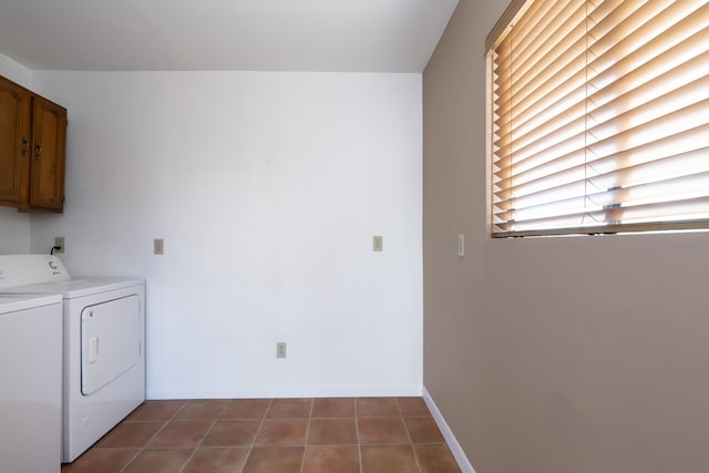 clothes washing area featuring dark tile patterned flooring, washer and dryer, and cabinets