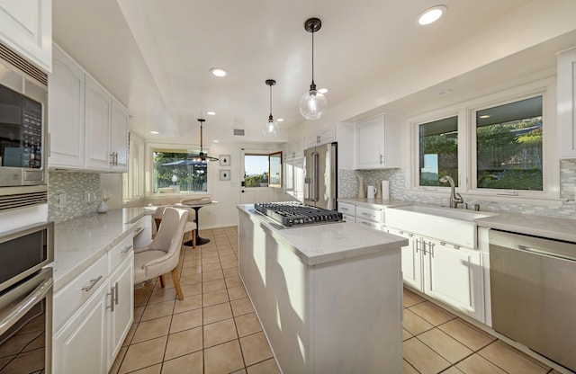 kitchen featuring a wealth of natural light, sink, hanging light fixtures, stainless steel appliances, and white cabinets