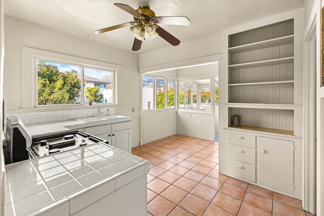 kitchen featuring tile counters, white cabinets, light tile patterned floors, and sink