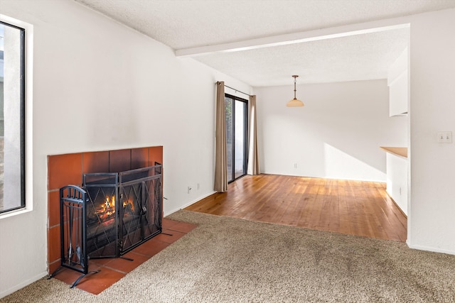 living room featuring a fireplace, beam ceiling, a textured ceiling, and hardwood / wood-style flooring