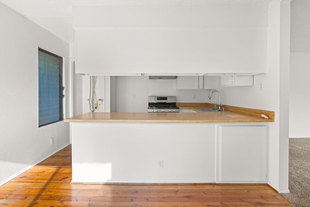 kitchen featuring kitchen peninsula, gas stove, hardwood / wood-style flooring, and sink