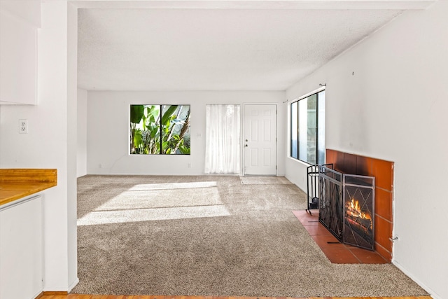 carpeted living room with a tiled fireplace and a textured ceiling