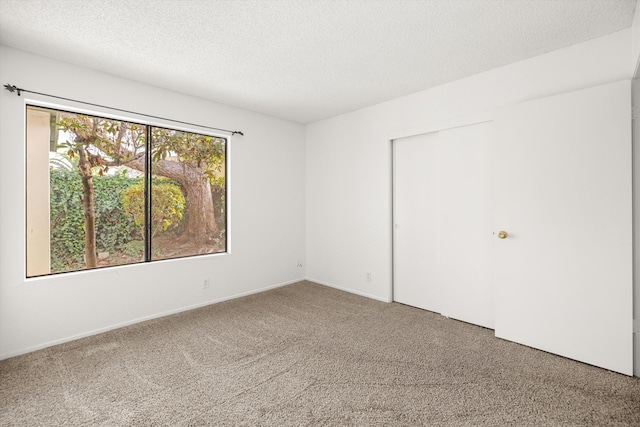 carpeted empty room featuring a textured ceiling