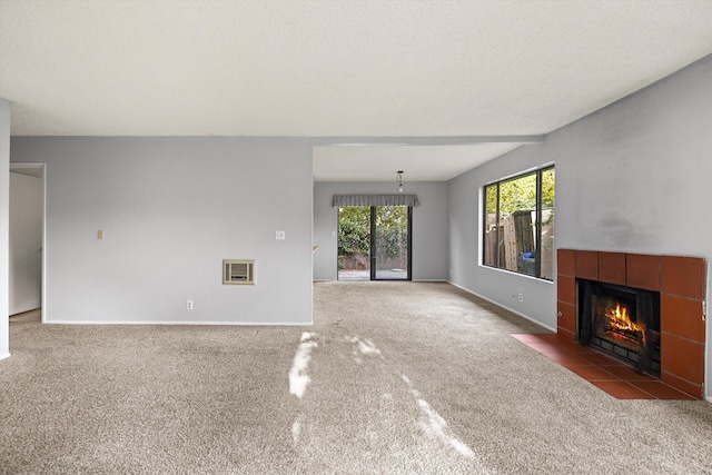 unfurnished living room featuring heating unit, carpet floors, and a tiled fireplace