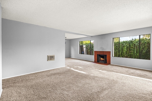 unfurnished living room featuring carpet, a textured ceiling, and a tile fireplace