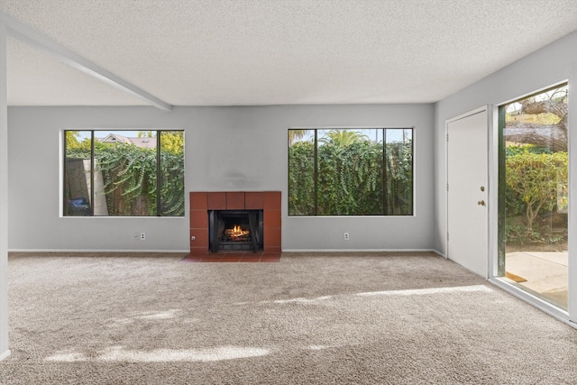 unfurnished living room with carpet flooring, a textured ceiling, and a wealth of natural light