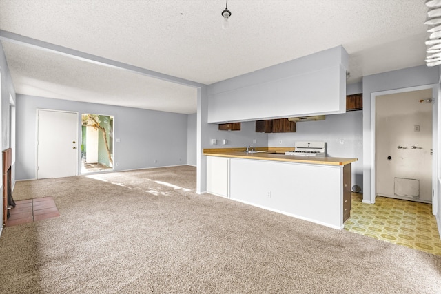 kitchen featuring kitchen peninsula, a textured ceiling, light colored carpet, and white range oven