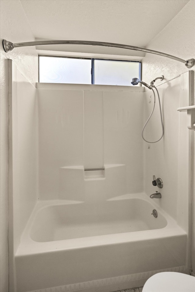 bathroom featuring a wealth of natural light, tub / shower combination, and toilet