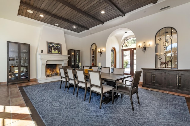 dining space featuring dark hardwood / wood-style floors, a large fireplace, wooden ceiling, and french doors