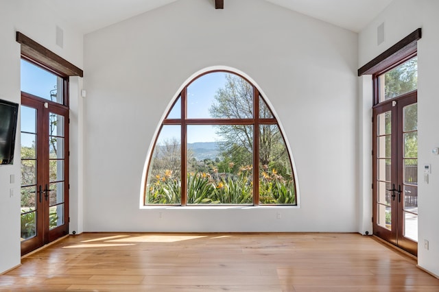 foyer entrance featuring french doors, high vaulted ceiling, and light wood-type flooring