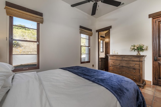 bedroom featuring ceiling fan, light tile patterned floors, and multiple windows