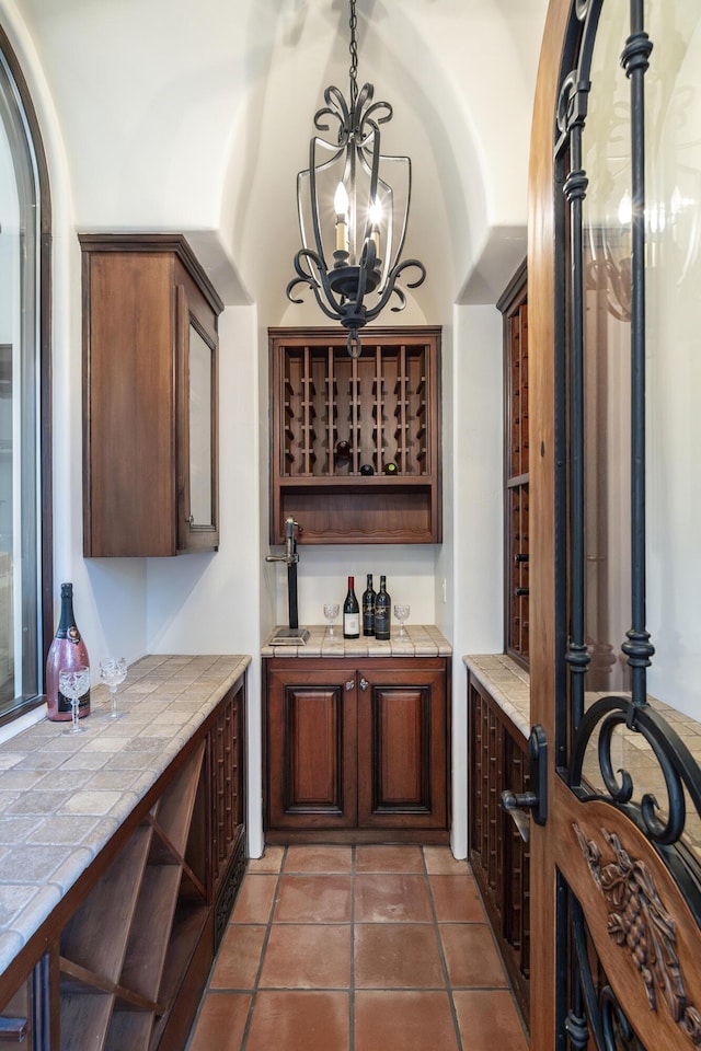 wine cellar featuring dark tile patterned floors and a notable chandelier