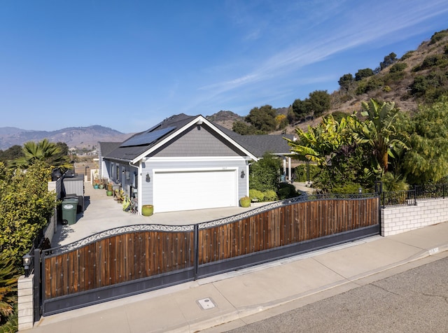 view of front facade with a mountain view, a garage, and solar panels