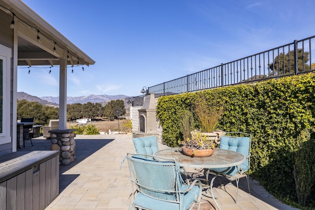 view of patio with a mountain view and exterior fireplace