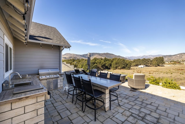 view of patio with area for grilling, a mountain view, sink, and a grill