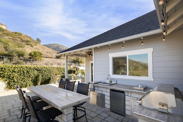 view of patio / terrace with area for grilling, ceiling fan, sink, a mountain view, and a grill