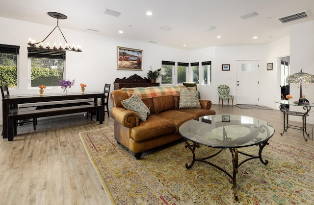 living room with plenty of natural light, light wood-type flooring, and a chandelier