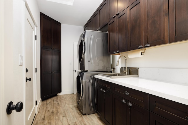 laundry room featuring stacked washer / dryer, light hardwood / wood-style flooring, cabinets, and sink