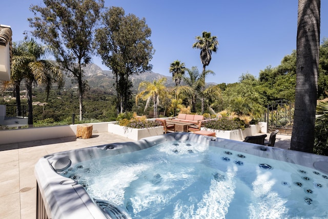 view of swimming pool featuring outdoor lounge area, a mountain view, a patio, and a hot tub