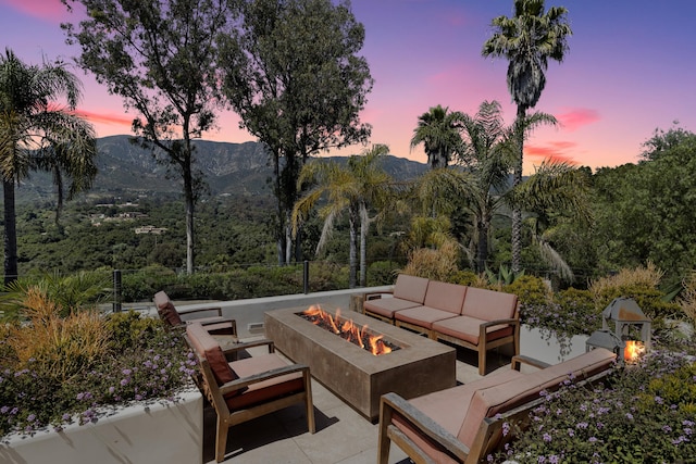 patio terrace at dusk with a mountain view and an outdoor living space with a fire pit