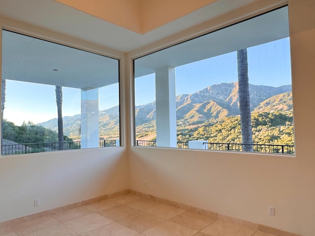 unfurnished room with a mountain view and light tile patterned floors