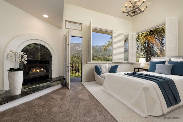 bedroom featuring lofted ceiling, access to outside, carpet flooring, a notable chandelier, and a tiled fireplace