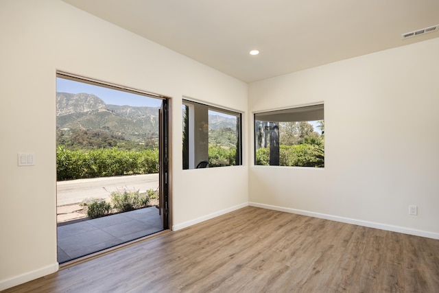 spare room featuring a mountain view and light wood-type flooring