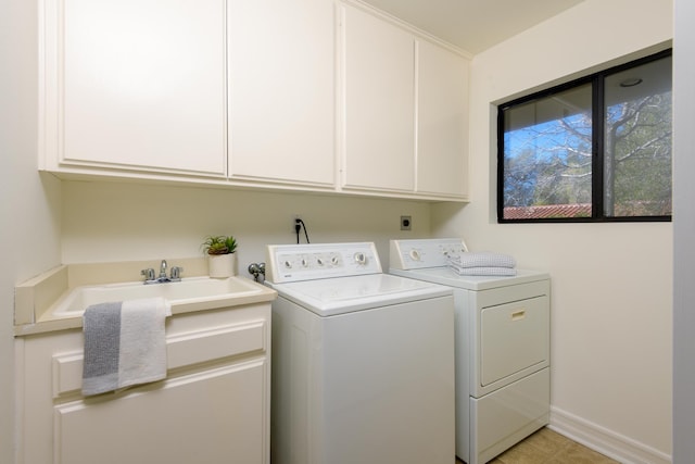 laundry area with cabinet space, baseboards, a sink, and washing machine and clothes dryer