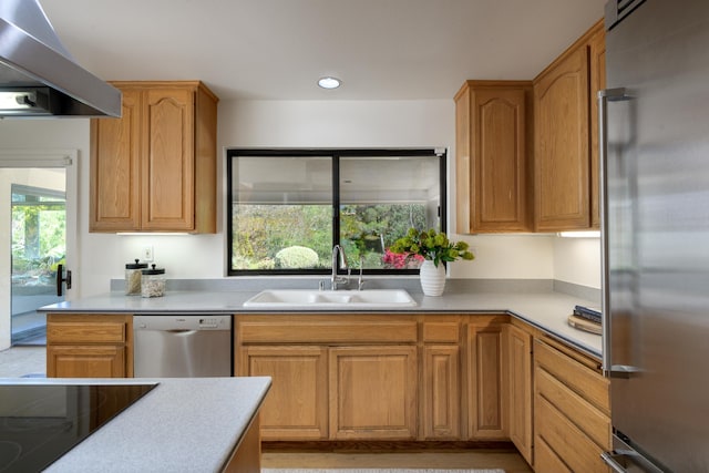 kitchen featuring stainless steel appliances, recessed lighting, light countertops, a sink, and wall chimney range hood