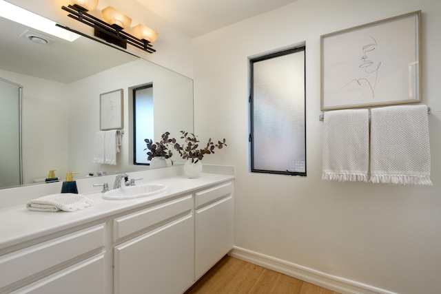 bathroom with wood finished floors, vanity, and baseboards